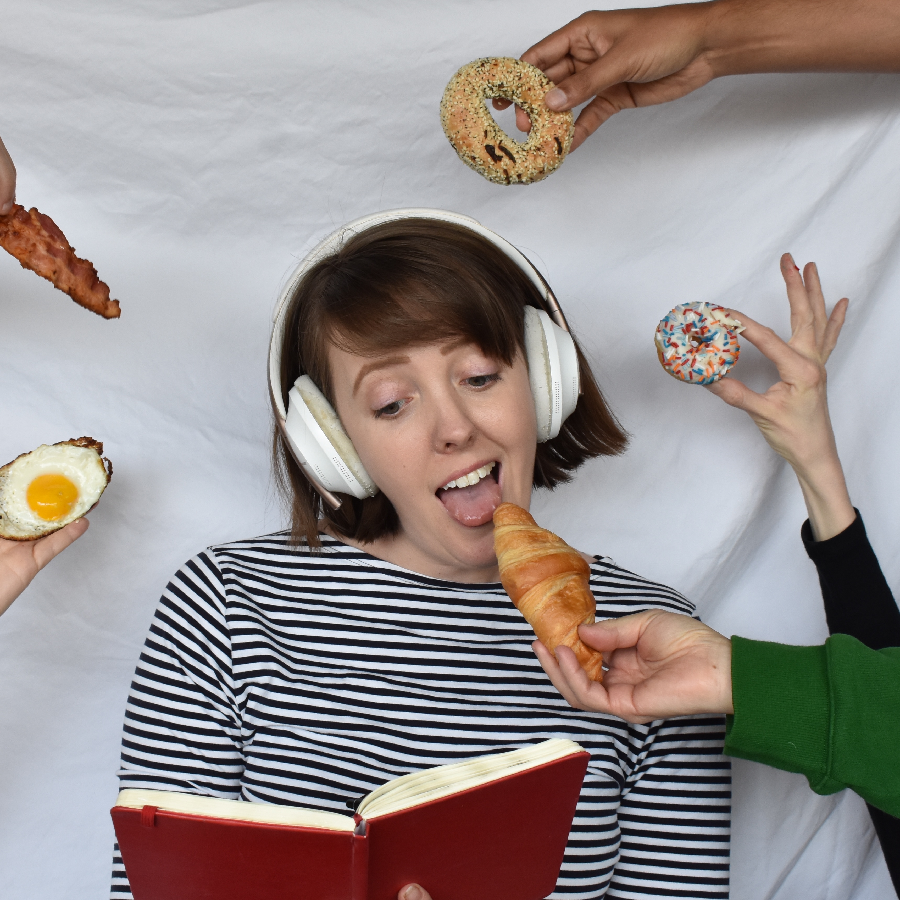 Frank is listening to music, tilting her head looking up at a bagel being passed to her.