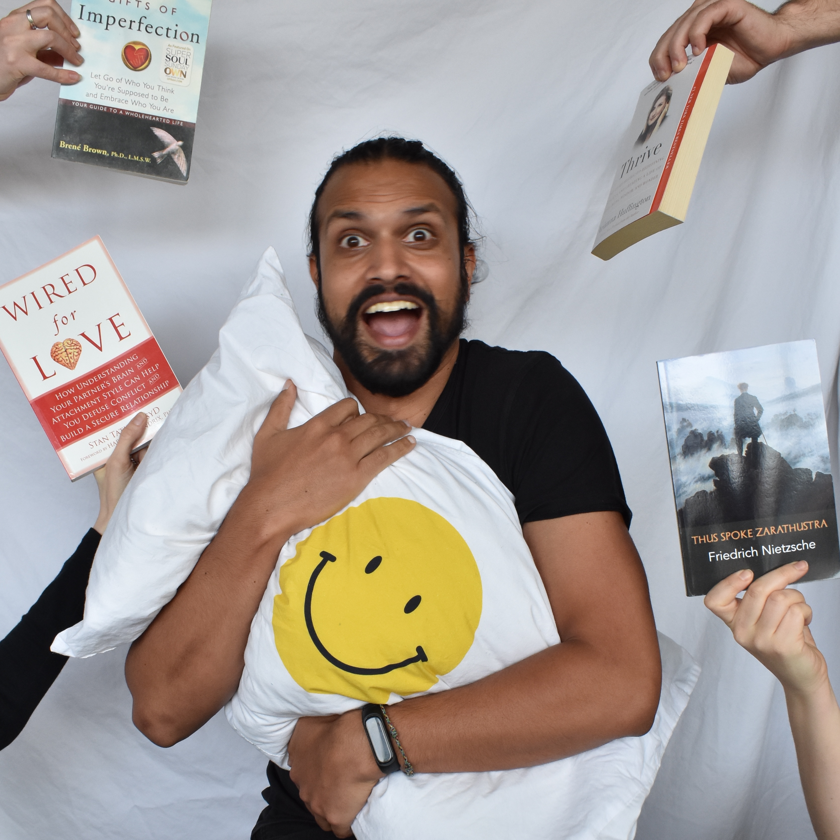 Janek with an open mouth smile holding a white pillow with a yellow smiley face