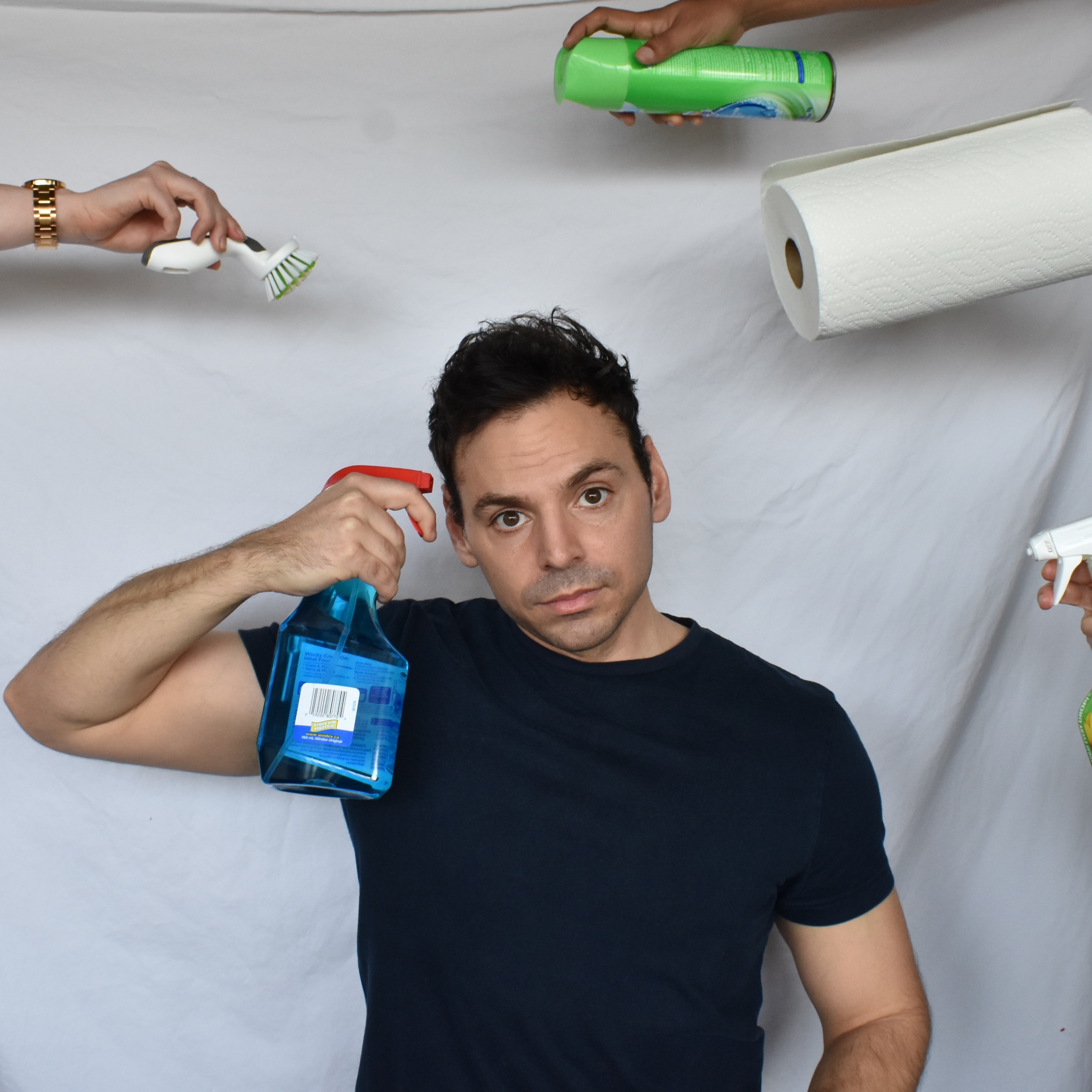 Thomas looking at the viewer as he holds a bottle of windex to his temple
