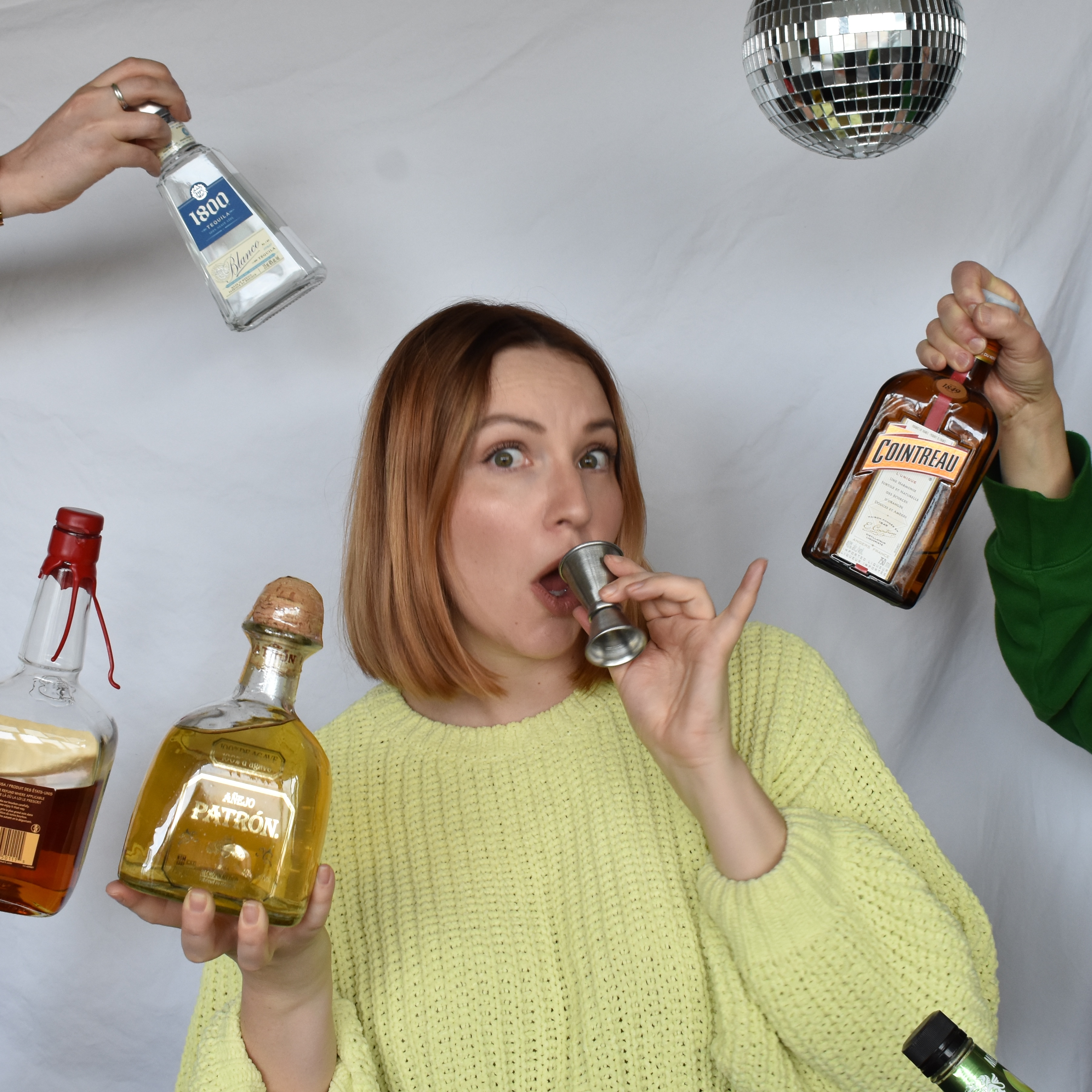 Virginia holding a shot glass to her mouth looking semi-surprised at the viewer
